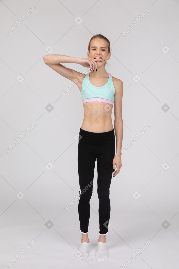Front view of a teen girl in sportswear biting her finger
