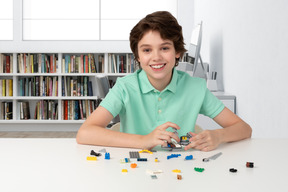 A boy sitting at a table with legos all around him