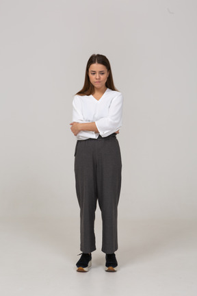 Front view of an upset young lady in office clothing putting hands on belly