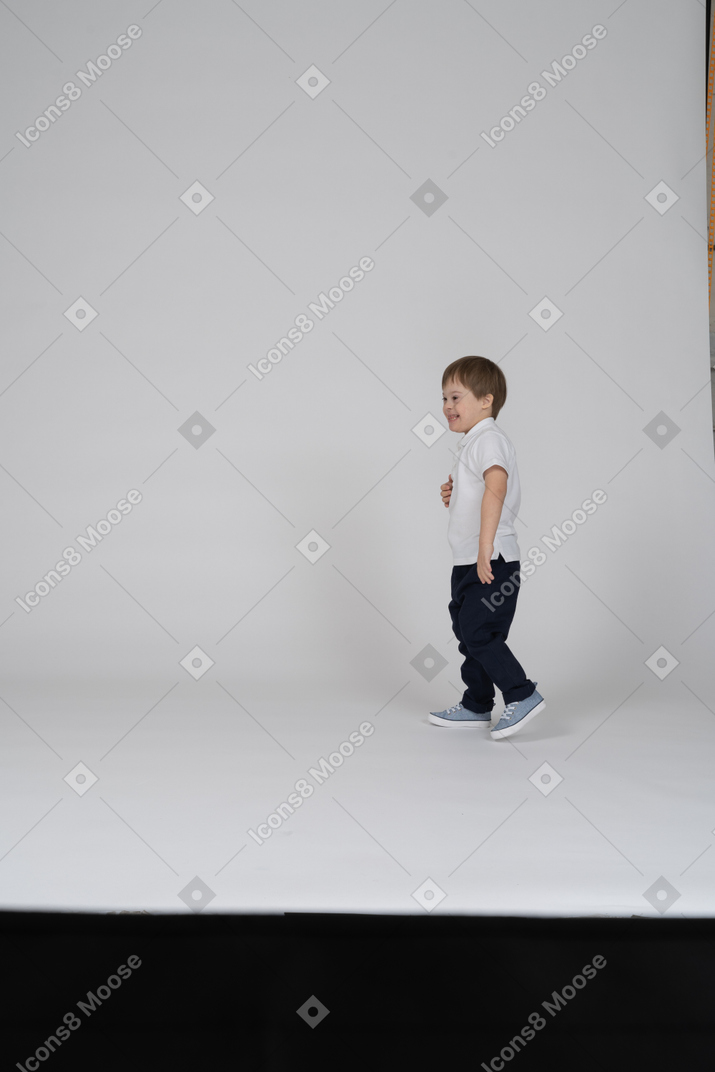 Улыбающийся маленький мальчик стоит вдалеке