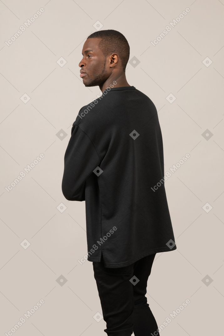 Three-quarter back view of young man looking aside