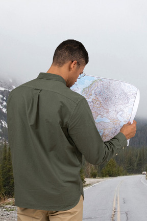 A man looking at a map on the side of a road