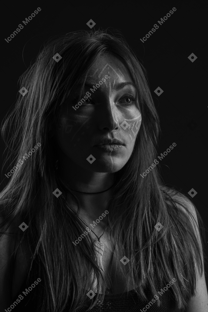Three-quarter dark portrait of a young woman with face art