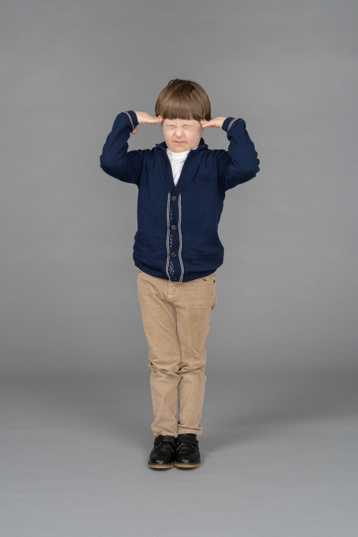 A little boy putting hands on his head