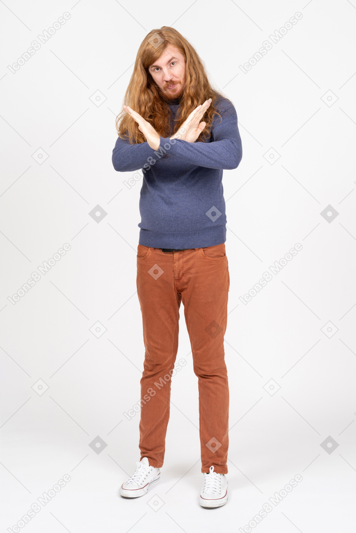 Vista frontal de un joven con ropa informal que muestra la señal de alto