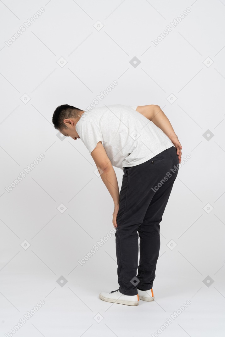 Side view of a man bending down and touching hurting knee