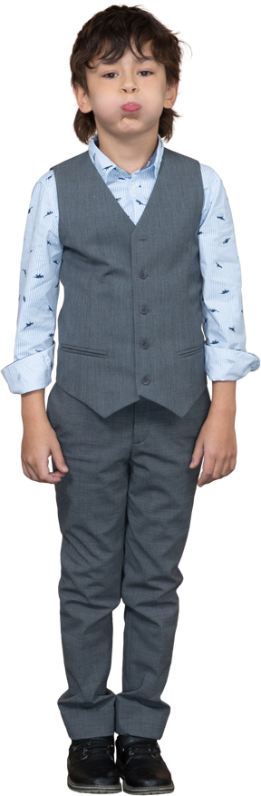 Front view of a boy in grey suit puffing cheeks
