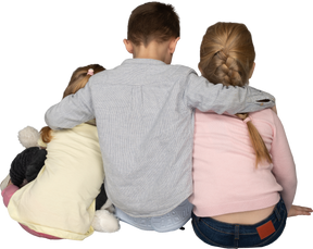 Boy embracing two little girls back to camera