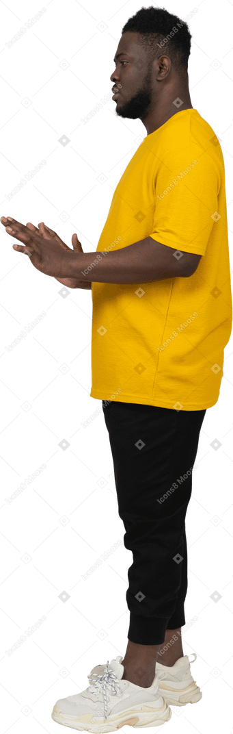 彼の腕を伸ばしている黄色のtシャツを着た若い浅黒い肌の男の側面図