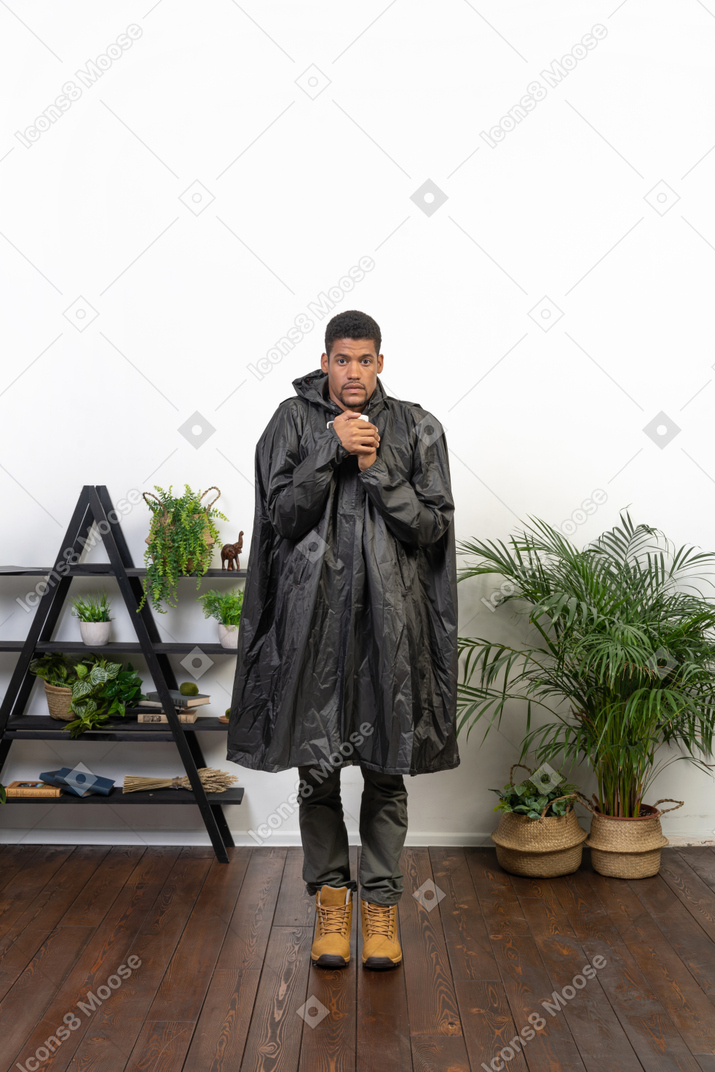 穿雨衣的男人试图用热茶取暖