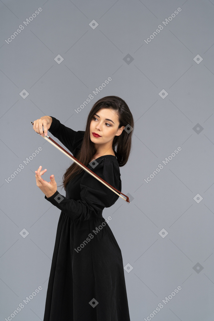 Three-quarter view of a young lady in black dress making an impression of playing the violin