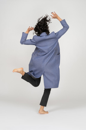 Back view of woman jumping on one leg