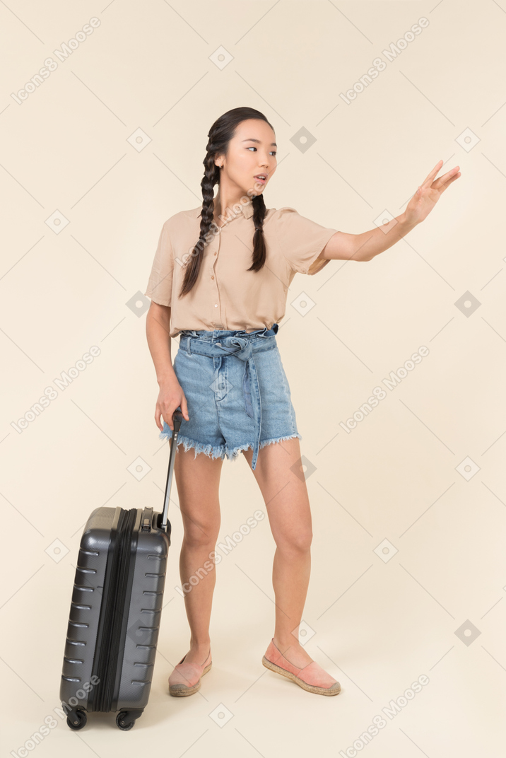 スーツケースを持ってタクシーを呼ぶ女性
