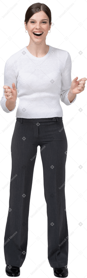 Front view of a delighted young woman in office clothing clenching fists