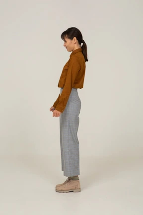 Vista lateral de una joven mujer asiática en calzones y blusa apretando los puños