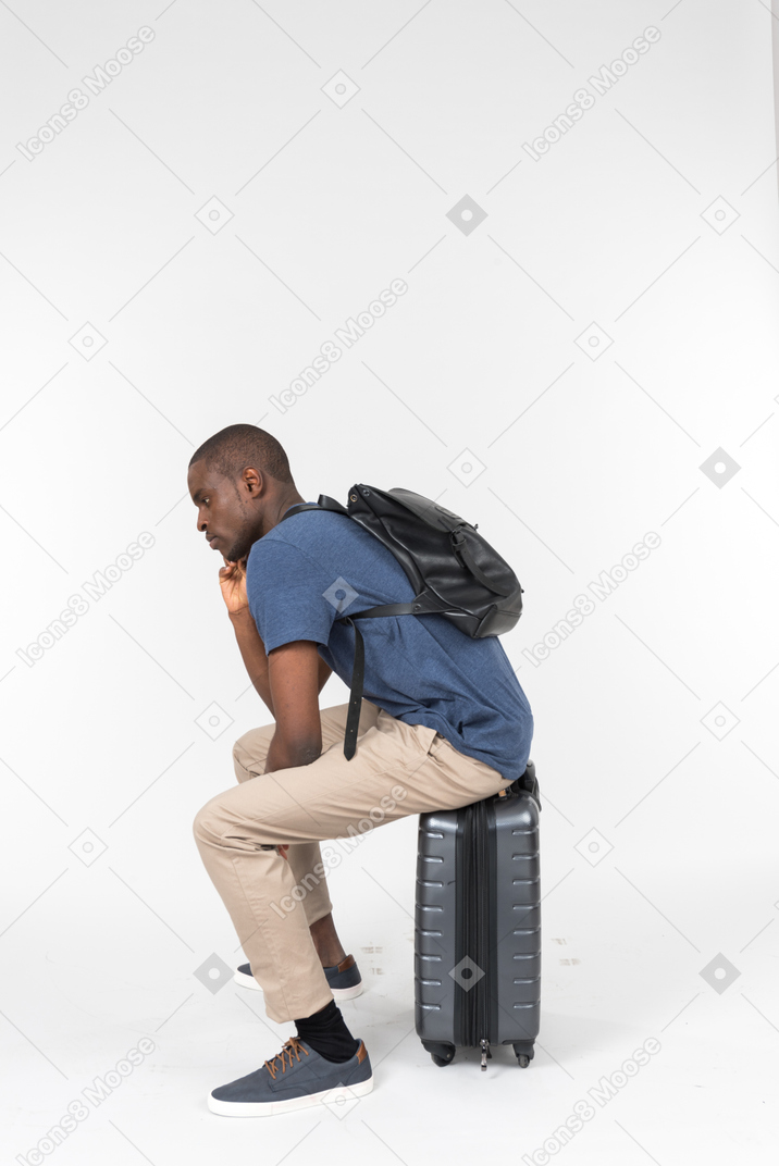 회색 짐에 앉아 생각에 잠겨있는 남성 관광