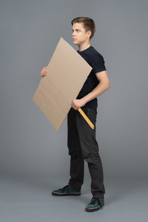 空白のポスターと立っている深刻な若い男