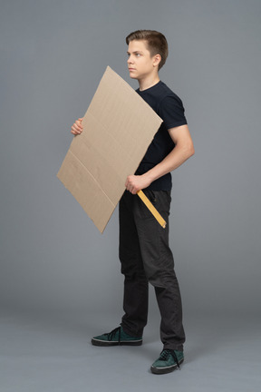 Serious young man standing with a blank  poster