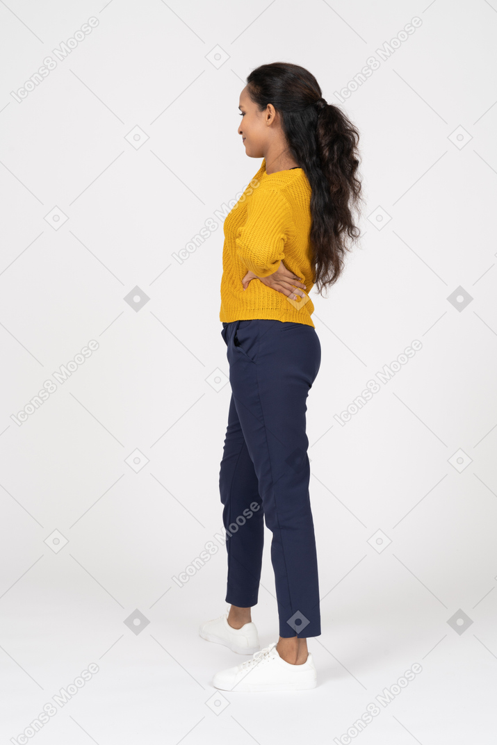 Side view of a girl in casual clothes posing with hands on hips