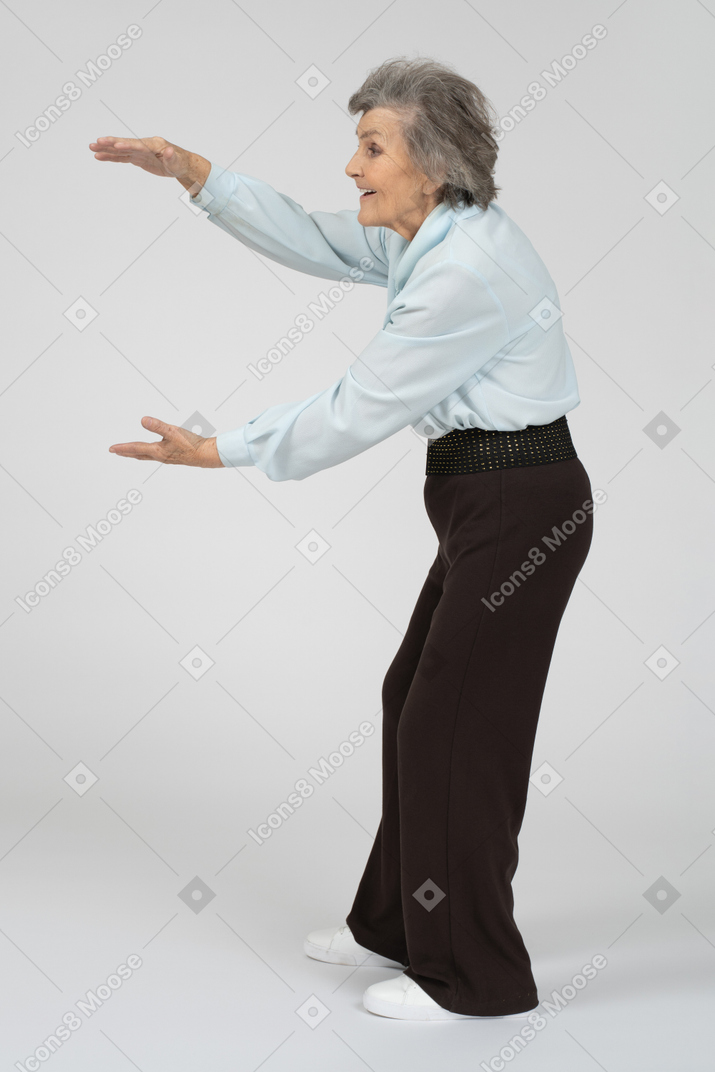 Пожилая женщина показывает размер обеими руками