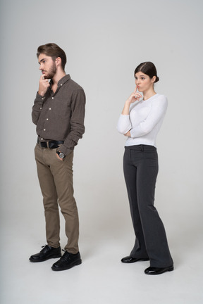 Dreiviertelansicht eines nachdenklichen jungen paares in bürokleidung, die das kinn berührt