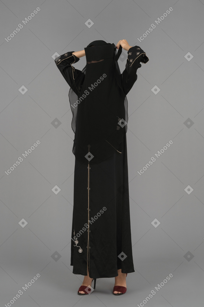 A muslim woman putting on a niqab