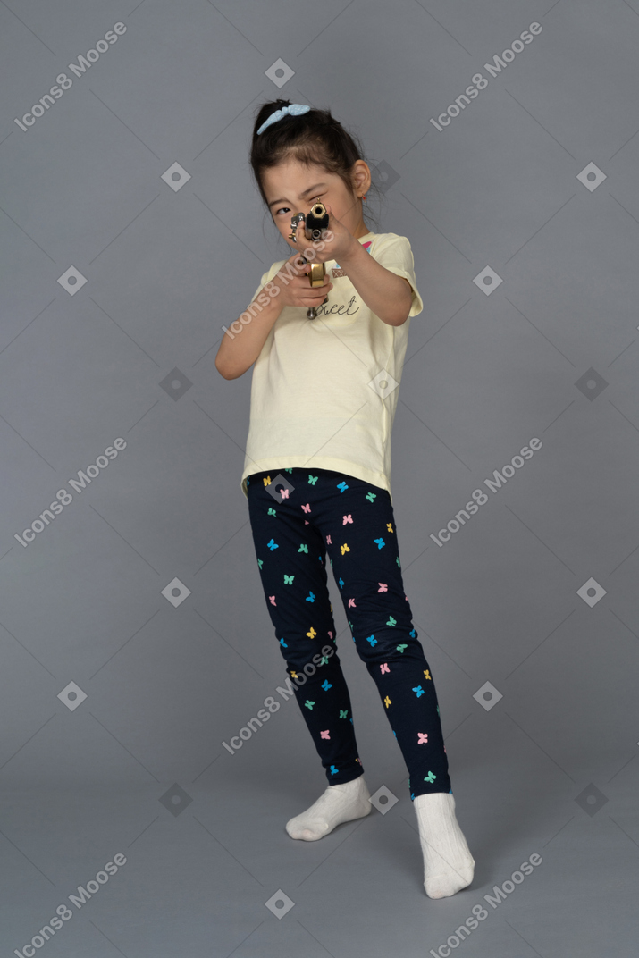 Portrait d'une petite fille visant un fusil de chasse