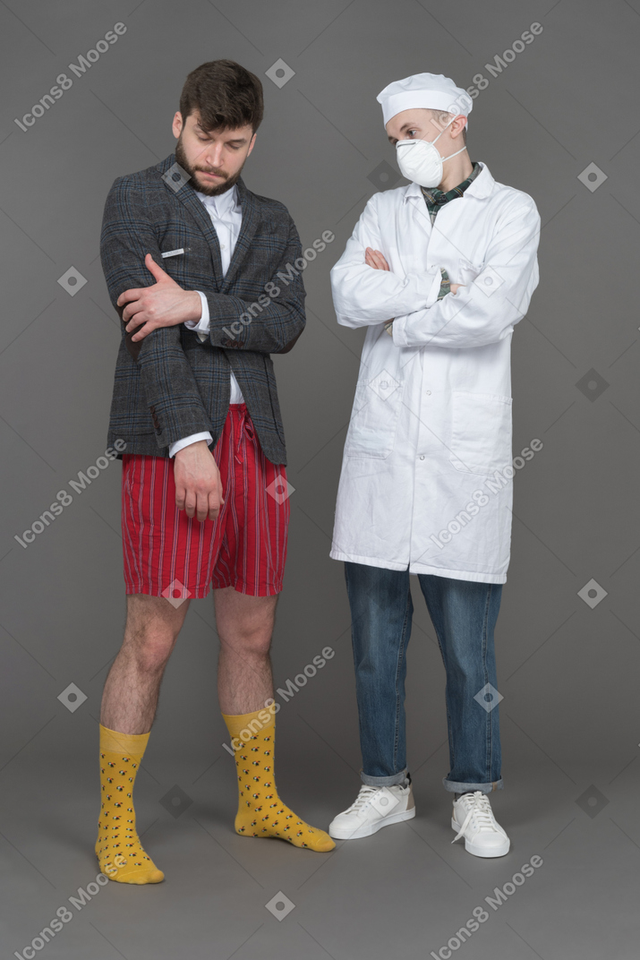 Young man holding his hand and standing with doctor