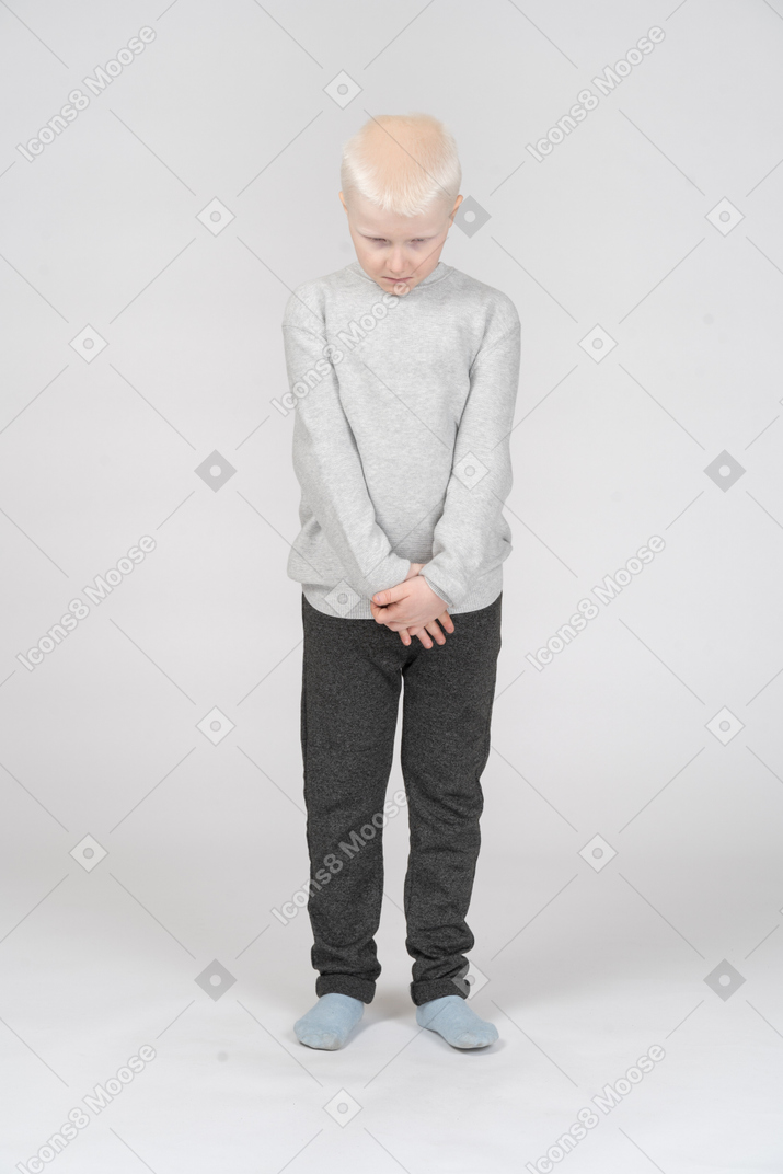 Vista frontale di un ragazzo bambino triste vergogna guardando in basso