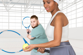 Two people holding tennis rackets and a ball