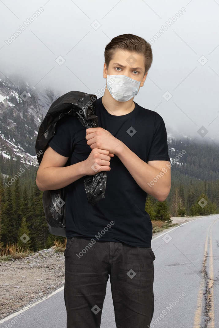 Man in facial mask carrying a plastic bag