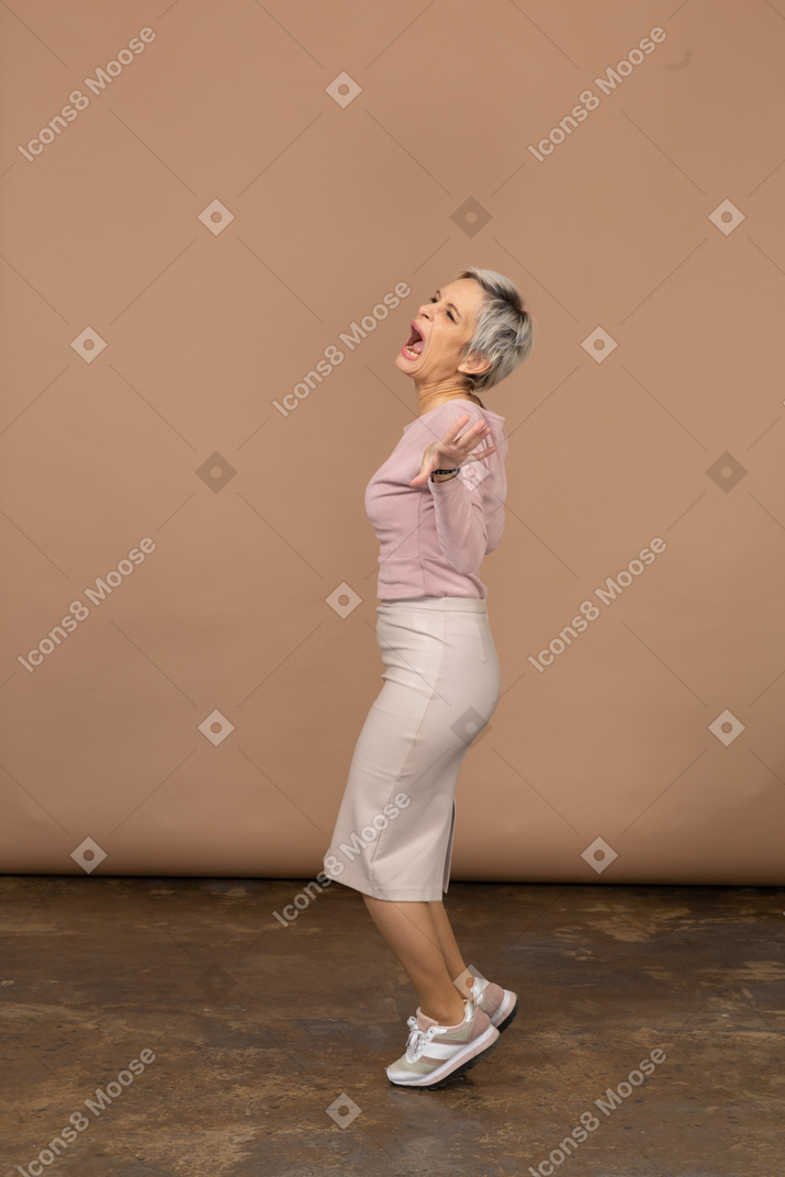 Vista lateral de uma mulher emocional em roupas casuais, na ponta dos pés e braços estendidos