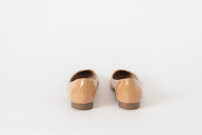 A back shot of a pair of beige lacquer low heel shoes