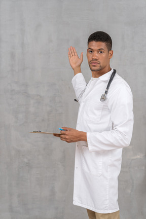 Doctor with stethoscope and clipboard pointing at something