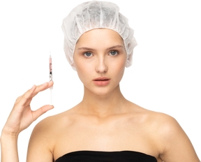 Young woman holding syringe while looking at camera