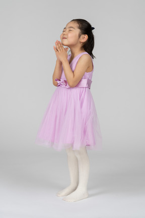 Dreamy little girl in pink dress making a wish