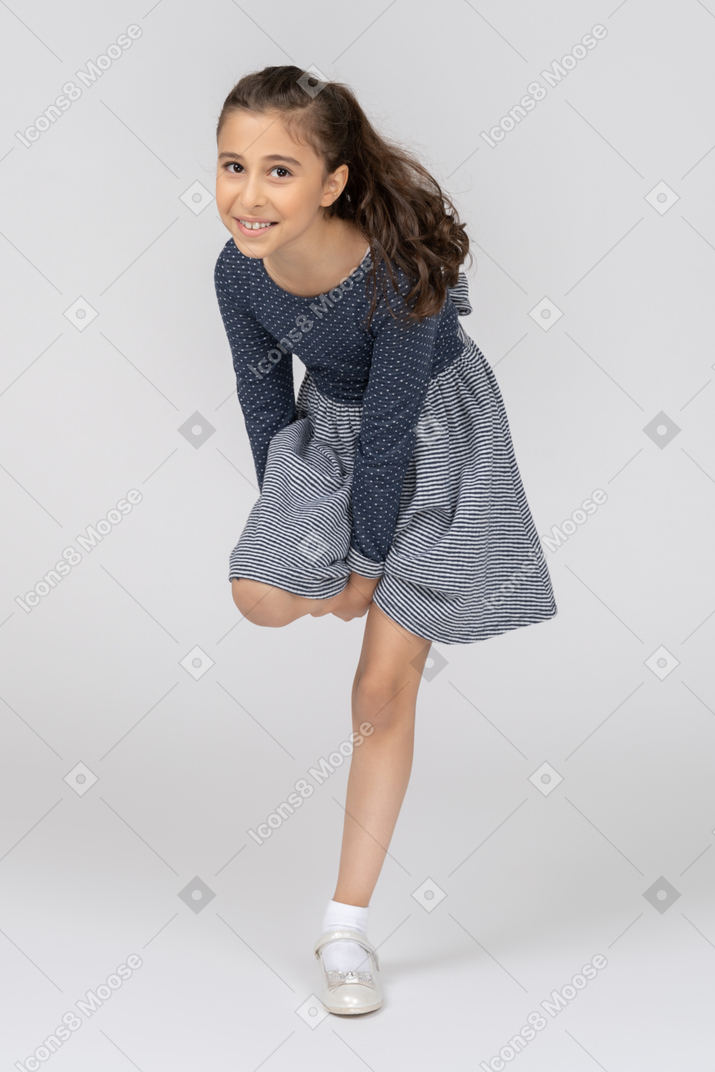 A young girl in a blue dress is doing a trick