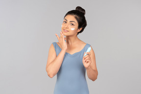 Young indian woman in blue tank top applying face cream