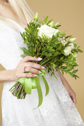 Sposa con un anello su una mano che tiene il bouquet da sposa