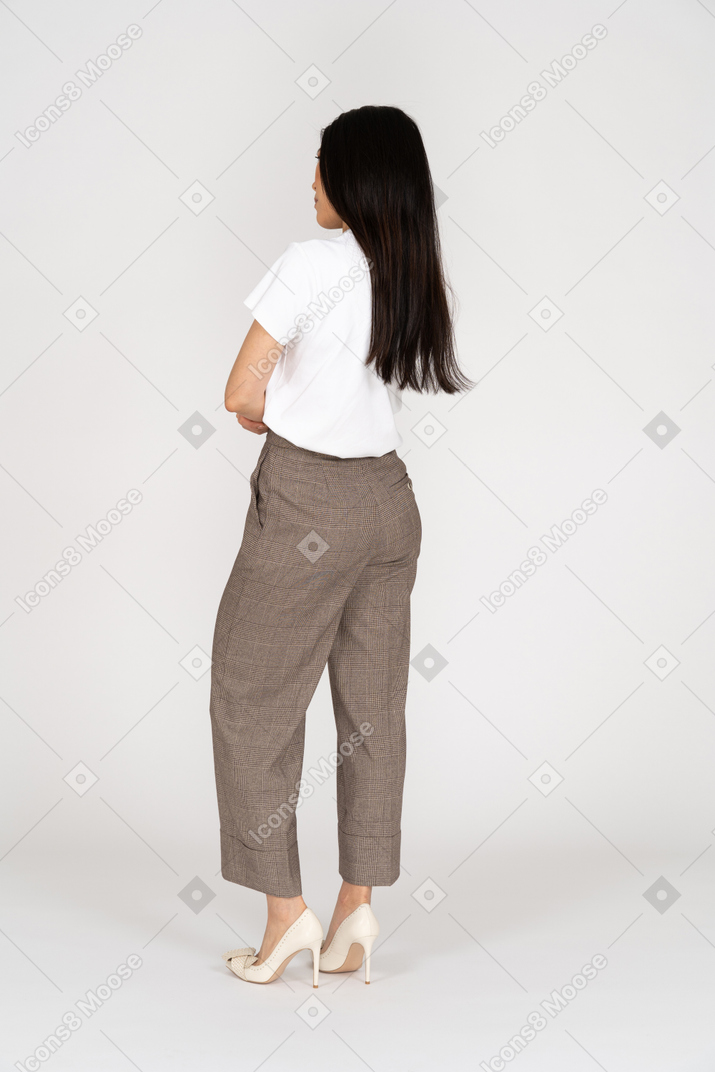 Vista posterior de tres cuartos de una joven disgustada en calzones y camiseta cruzando las manos