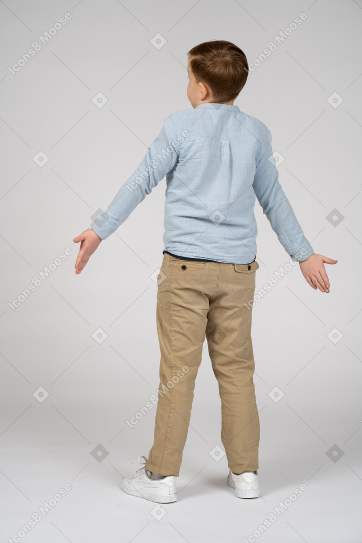 Back view of a boy standing with outstretched arms