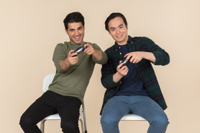 Interracial friends sitting in chairs and playing video games