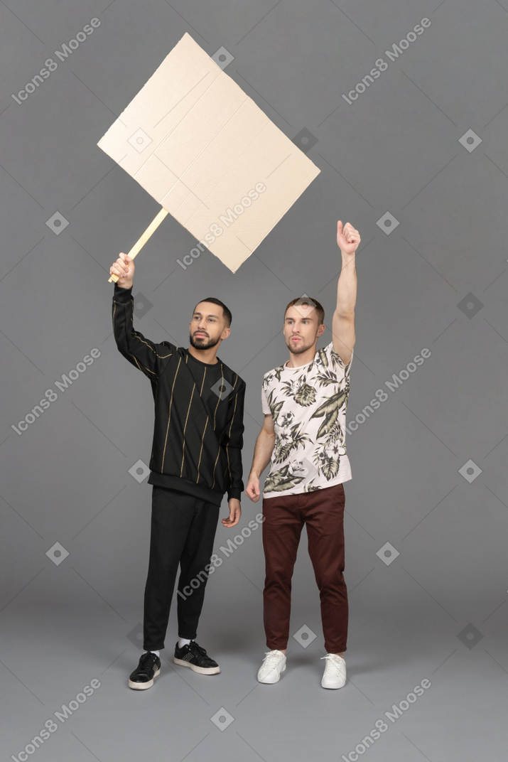 Front view of two young men waving a billboard passionately