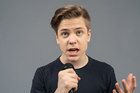 Serious young man speaking into microphone