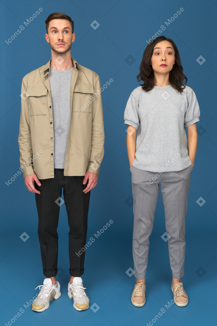 Surprised man and woman standing with raised eyebrows