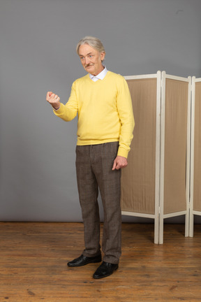 Vista de tres cuartos de un anciano astuto sonriente apretando el puño