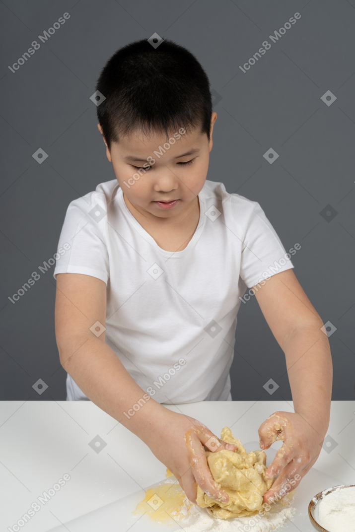 A little boy kneading a dough