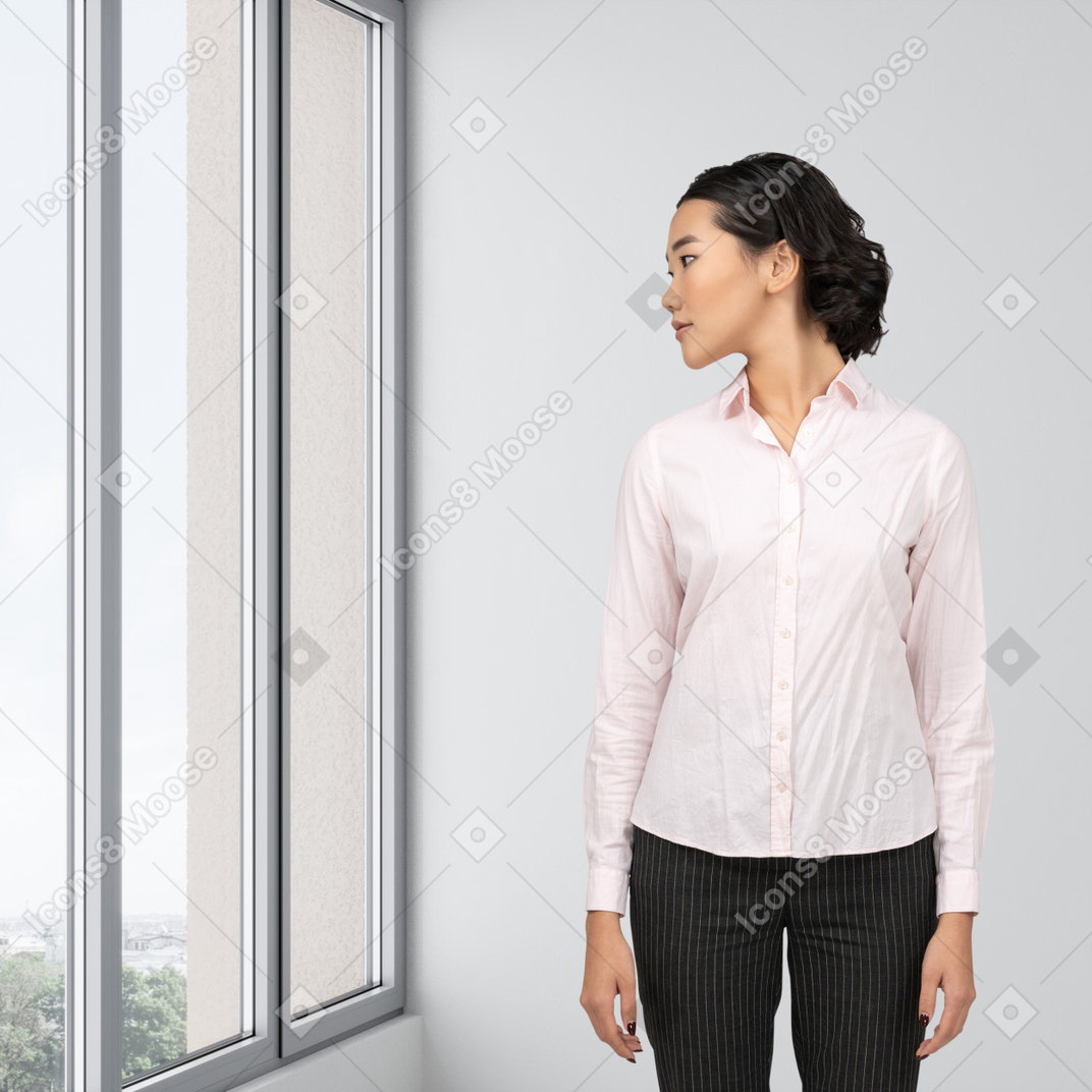 A woman standing in front of a window looking out the window