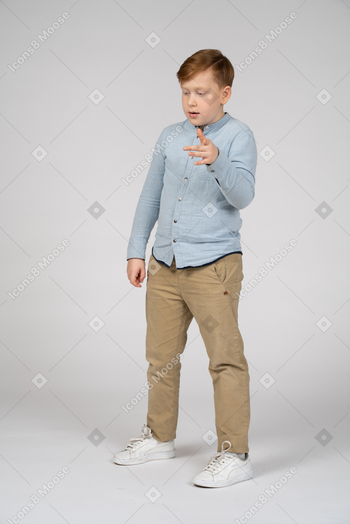 Niño de pie y gesticulando con la mano