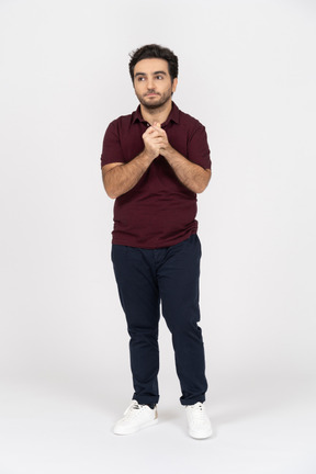 A young man standing with his hands folded